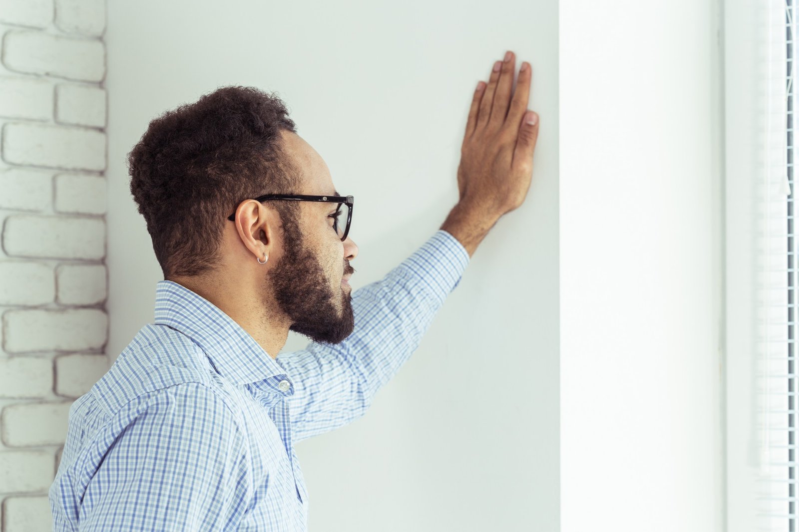 Person betrachtet besorgt eine feuchte Wand im Wohnraum
