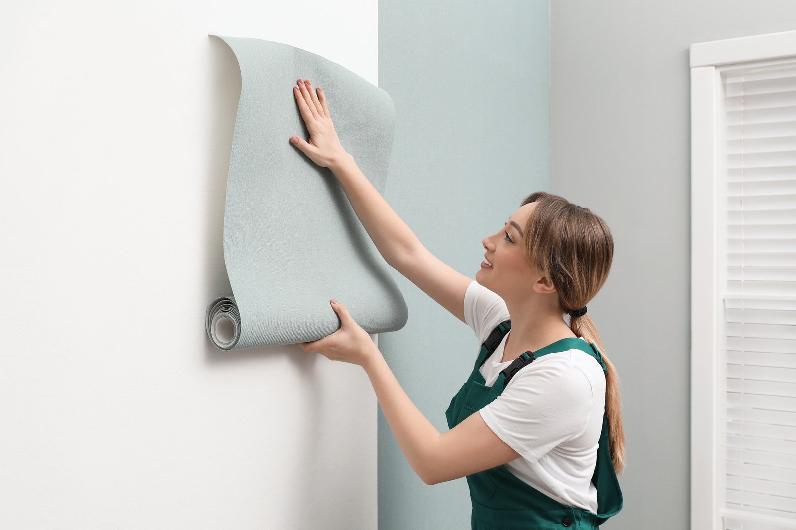 Jemand tapeziert eine frisch sanierte Wand